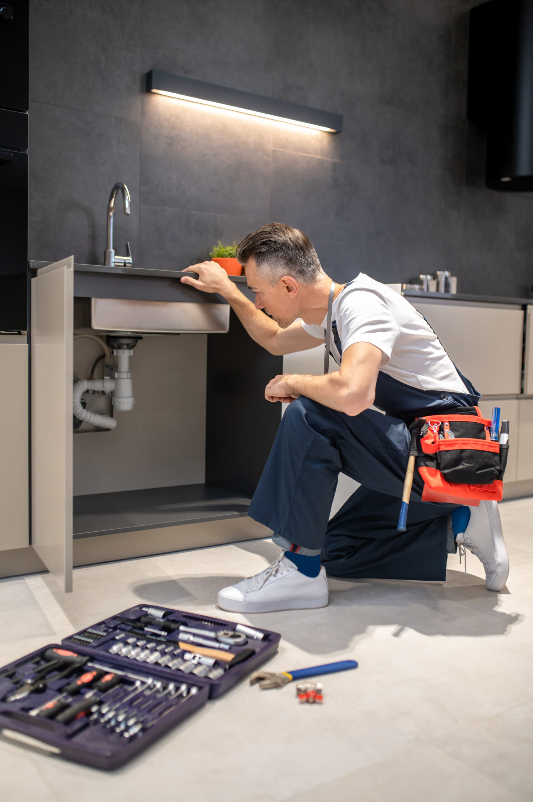 A plumber using a drain cleaning machine to clear a clogged drain