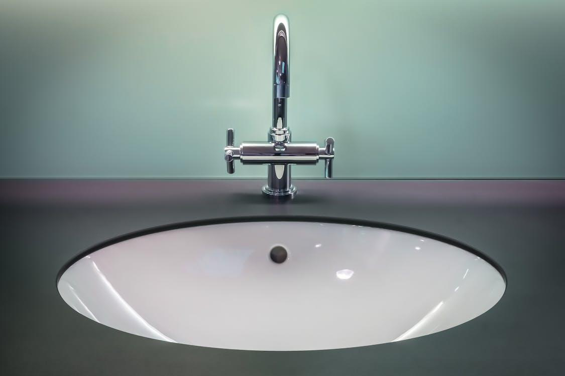 A modern black and white vanity with a stainless steel faucet