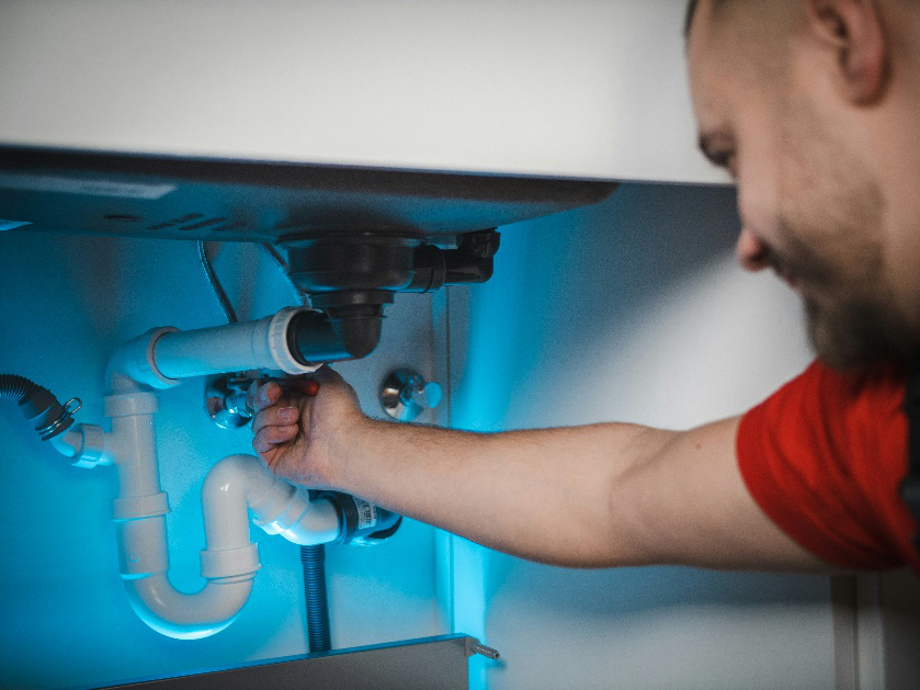 A plumber working under a sink.